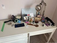 Overview of various office supplies on a white desk featuring a silver desk lamp, letter openers, tape dispenser, and other assorted items.
