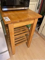 Front view of the wooden kitchen island with microwave on top, showing two slatted shelves and wood grain.