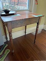 Wooden side table positioned near a window showcasing turned legs and aged wood surface.