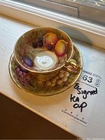 Cup resting on matching saucer at window sill, pattern visible