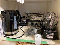 Overview of the lot on a shelf showing all four appliances with cords and manual visible.
