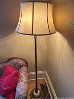 Full view of vintage floor lamp lit, showing fabric shade and metal/marble base next to patterned sofa.