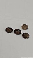 Four natural oval faceted Smokey quartz gemstones on a white background, showing their calibrated 8x6mm size and consistent color tone.