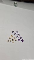 Photo showing a group of loose round faceted gemstones in two colors: purple amethyst and yellow citrine, arranged on a white background