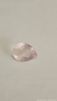 Clear image of pear shaped checkerboard cut rose quartz gemstone showing soft pink color and facets.