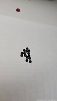 Lot of small round jet black onyx cabochon gemstones on white background, showing the quantity and shape of stones.
