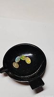 Four natural oval cut Ethiopian opals displayed on a black circular dish, showing play of color including green, yellow, and orange flashes.