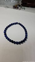 Photo of a circular stretch bracelet of polished round lapis lazuli beads in deep blue color.