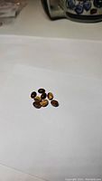 Photo showing a parcel of eight natural tiger's eye oval cabochon gemstones placed on a white sheet.