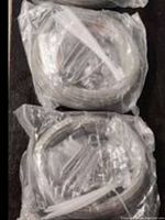 Three plastic-sealed rolls of stainless steel wire cable with mounting hardware visible inside the packaging.