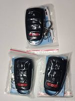 Photo of three programmable garage door remotes in plastic packaging with key rings, showing button labels A, B, C, D.