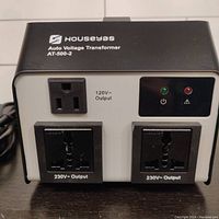 Front view of the Houseyas 500W Auto Voltage Transformer showing one 120V output and two 230V universal output sockets, and indicator lights.