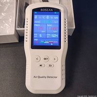Device powered on showing color LCD with air quality data including HCHO, PM2.5, TVOC, CO, CO2, AQI, temperature, and humidity