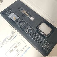 Complete set in black foam packaging: stainless steel bracelet band, pin pusher tool, extra pins packed in plastic, and protective Apple iWatch case holder.