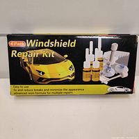 Front of box showing 4 pack windshield repair kit with image of sports car and depiction of resin bottles and repair tools.