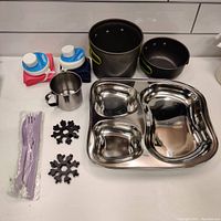 Full lot contents showing collapsible water bottles, cooking pots, coffee cup, multi-tools, silicone utensils, and divided stainless steel tray.