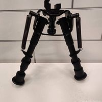 Front view showing collapsible tripod with retractable legs and spring arms for support.