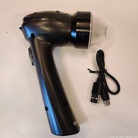 Full view of the black electric grinder with attached transparent lid and USB charging cable beside it.