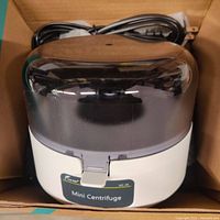 Photo of the Lab Fish Mini Centrifuge MC-4K with transparent lid in a cardboard box.