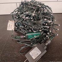 Tangled and wound RGB LED string lighting with power plug and inline controller visible.