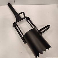 Full view of the steel planter tool showing long handle and cutting end with jagged edges and side handles