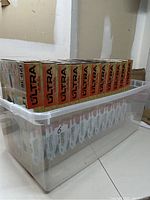 Clear plastic bin holding 11 boxed Nerf Ultra Amp blasters stacked in two rows
