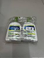 Two sealed bottles of Cetaphil lotion with green pump dispensers in clear packaging, showing front label with branding and product info.