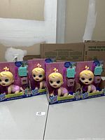 Four boxed Baby Alive dolls arranged side-by-side on a table, showing front of boxes with doll faces visible