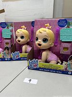 Four Baby Alive dolls in original pink packaging with feeding accessories visible.