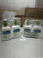 Four bottles of Cetaphil DailyAdvance Lotion in two pairs, sealed in plastic wrapping, displayed on a table.
