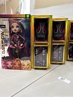 Photo showing one boxed Rainbow High doll with visible accessories inside the packaging and five additional boxed shoe and glove accessory sets.