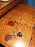 Full view of the antique bronze and vintage jade Buddha pendants with chain displayed on wooden surface