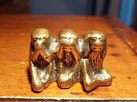 Front view of the brass three wise monkeys paperweight showing the monkeys covering eyes, ears, and mouth.