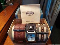Fossil men's three piece quartz watch set displayed in original box with three leather straps and warranty booklet
