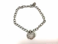 Full view of the silver-tone linked bracelet with heart-shaped pendant charm encrusted with Swarovski crystals, laid flat.