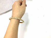 Gold tone open cuff bracelet with clear Swarovski crystals worn on wrist, showing size and sparkle under lighting.