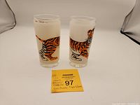 Two frosted vintage glasses showing the walking tiger design side by side with a note card.