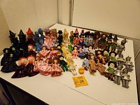 Full lot collection displayed on white corner surface showing 53 dolls in varied costumes from Madame Alexander's Wizard of Oz series.