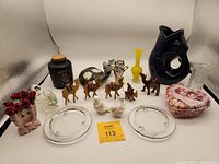 Full view of all items in lot showing arrangement of collectibles including glassware, ceramics, wood carvings, and decorative box