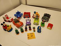 Overview of the 15 assorted Disney vehicles and character toys showing varied sizes and colors on table.
