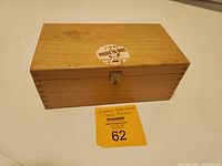 Closed view of wooden rectangular box with dovetail joints and clasp, labeled with auction sticker.