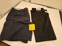 Both Cherokee cargo shorts and Braggi pants folded on table with visible tags.