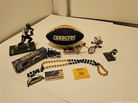 Wide shot showing all Chargers collectibles including football, statues, motorcycle model, 18 wheeler truck, magnet, Mardi Gras beads and small statue on white surface.
