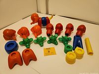 Image showing multiple plastic toy parts including animal heads and body pieces, arranged on a white surface against a corner background.