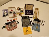 Full view of the vintage costume jewelry lot including multiple earrings, necklaces, bracelets, some packaged in boxes and pouches. Notable items include Halloween and Christmas themed earrings like spiders and crabs.