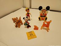 Full view of all seven vintage Disney collectible items on a white surface including toy figures and ornaments.