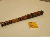 Image showing full length of vintage hand carved wooden piñata bat with colorful Mexican patterns.