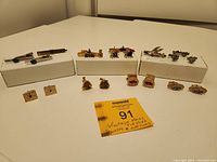 Full lot of vintage men's jewelry items arranged on white display blocks including tie clips and cuff links.