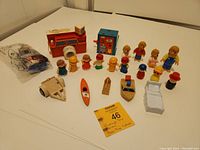 Full view of multiple vintage toy figures including Fisher Price and other miscellaneous pieces laid out on a white surface.