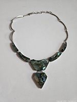 Front wide view of the vintage sterling silver and abalone necklace showing full length and detail of shell pieces and silver chain links.